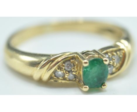 An 18ct gold&nbsp; emerald and diamond ring. The ring set with a central oval mixed cut emerald&nbsp; flanked by round cut di