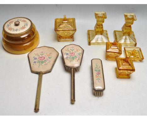 An early 20th Century Art Deco 1930's amber glass dressing table vanity set comprising of a mirror, brush, candlestick, trink