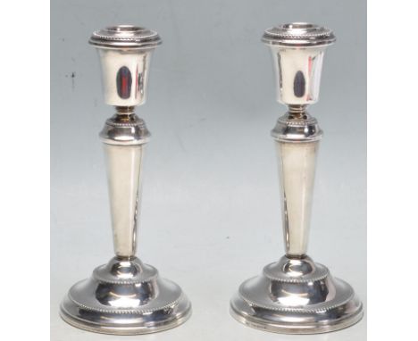 A pair of 1980’s silver hallmarked candlesticks having beaded decoration to the sconce, tapered capital, tapered column with 