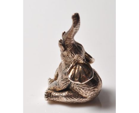 A stamped sterling silver figurine in the form of an elephant sitting with its trunk raised with moulded details. Stamped Ste