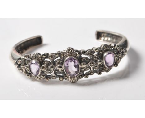 A stamped .925 sterling silver and marcasite bracelet bangle having a large central stone flanked by two smaller accent stone