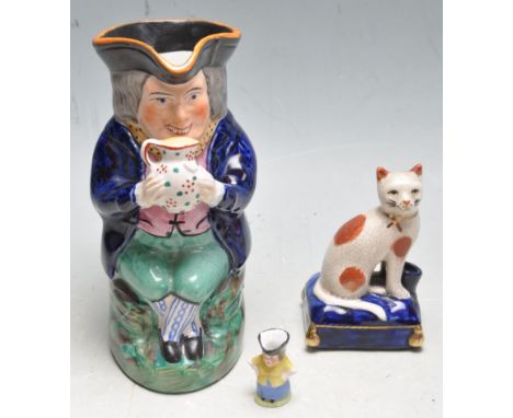 An antique early 20th century hand painted toby jug of a seated man drinking together with an unusual miniature toby jug of a