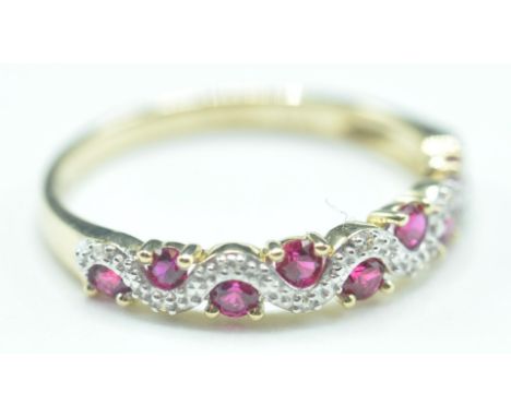 A 9ct gold synthetic ruby and diamond ring. The ring having alternating&nbsp; ruby and diamond within a 9ct gold band. Marked