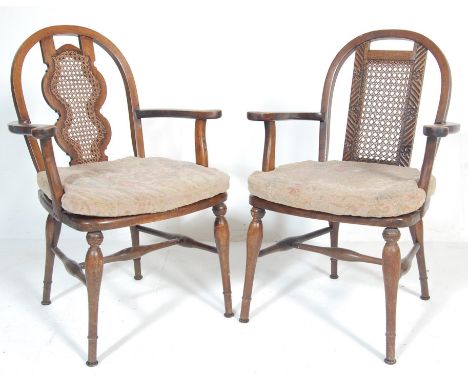 A pair of late 20th century oak dining chairs having a hoop back with a rattan and carved back splat, shaped elbow rests, pan
