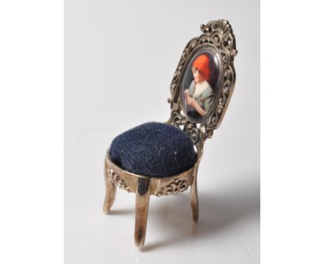 A stamped 925 sterling silver pin cushion in the form of a chair having an enamelled panel with a classical picture to the ba