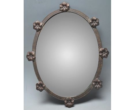 An early 20th Century wall hanging mirror of small proportions having a cast metal fluted frame with applied eight applied fl