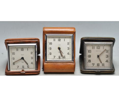 A set of three vintage 1950s mid 20th century leather bound portable travel clocks&nbsp;all having folding mechanisms. Makers