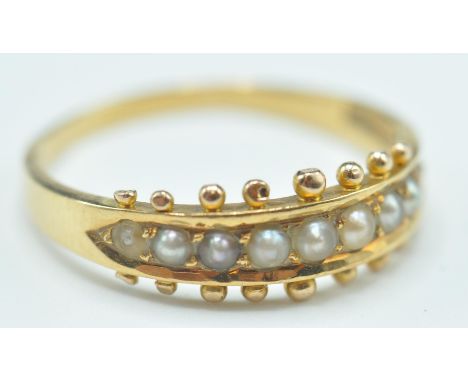 An early 20th century 18ct gold and half pearl ring. The ring with channel set half pearls to plain tapering shank af. Stampe