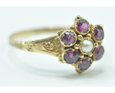 A 19th Century Victorian ring having a flower head set with a central pearl surrounded by six round cut garnets with engraved