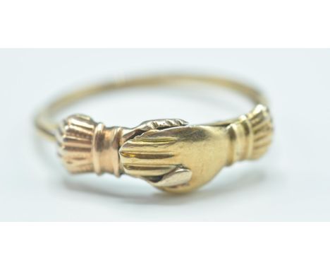 An antique gold clasp hand ring having two clasped hands having two fine interwoven rings with two clasped hands to the head 