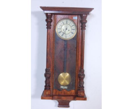 An early 20th century eight day mahogany cased Vienna regulator wall clock having a pediment top flanked by finials over a wh
