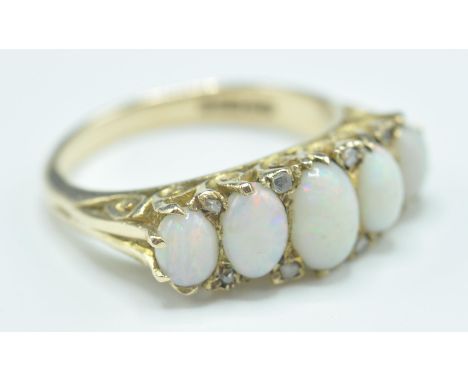 A hallmarked 9ct gold five stone ring set with five graduating oval opal cabochons with diamond accent stones set to the head