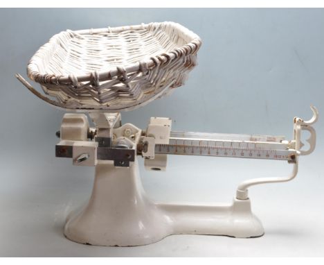 A mid century white enamel and cast iron doctors / midwife scale / balance having a wicker oval basket and a scale balance up