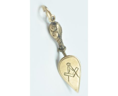 An antique 9ct gold Masonic trowel charm having engraved floral decoration and square and compasses to the verso. Unmarked bu