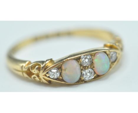 A late 19th Century Victorian 18ct gold ring having a navette shaped head set with two opal cabochons and four round cut diam