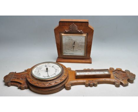 An early 20th century oak banjo barometer with carved decoration, white enamel barometer dial and white enamel thermometer di