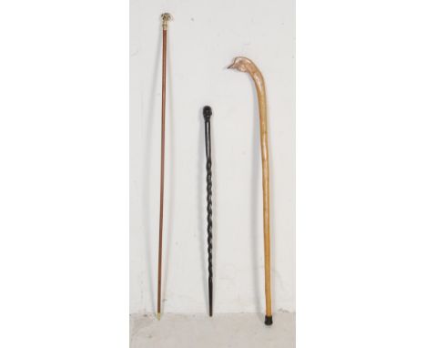 A collection of three vintage 20th century walking sticks comprising of an African hardwood cane with a mans head and barley 