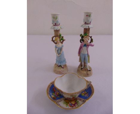 A pair of ceramic figural candlesticks and a Dresden cup and saucer, marks to the base