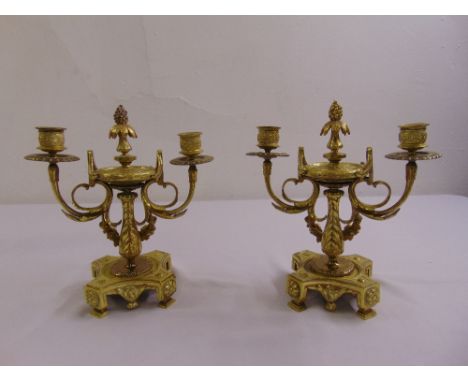 A pair of brass two light candelabra on shaped square bases with scroll supports