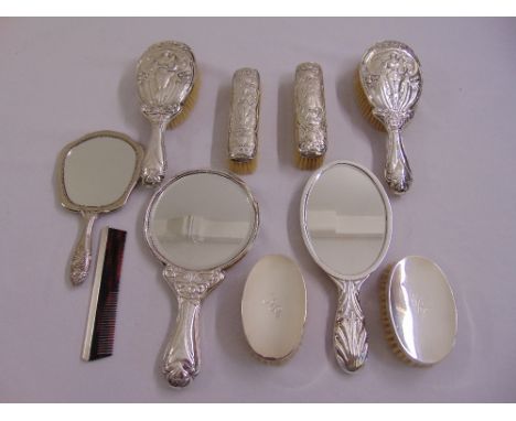 A silver mounted Art Nouveau style dressing table set comprising three hand mirrors, a pair of hair brushes, a pair of clothe