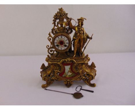 A gilded metal mantle clock the white enamel dial with Roman numerals supported by a figure in hunting attire, to include key
