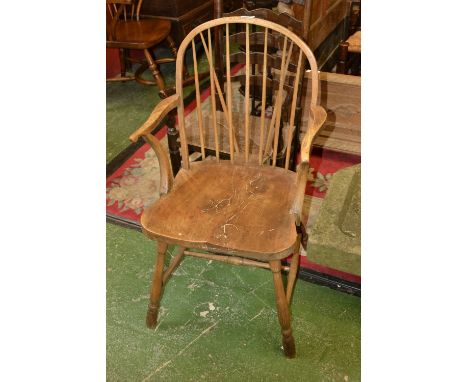 An early 19th century elm Windsor elbow chair, arched stick back, deep saddle seat, turned legs and stretcher, c.1820