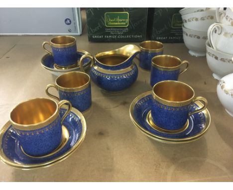A cauldron blue ground coffee set with applied gilt work . Comprising cups saucers and milk jug .