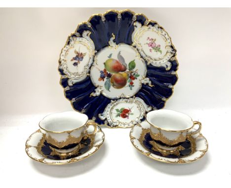 A Meissen porcelain cabinet plate with hand painted floral and fruit design, together with two gilt and royal blue Meissen cu