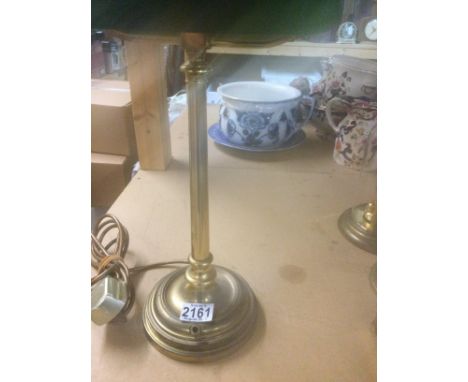 A brass students lamp with green shade .