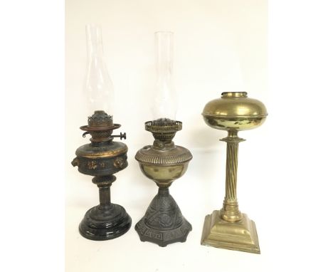Oil lamps including a late 19th century brass example with engraving, cast iron and brass lamp with a glass shade and a lamp 
