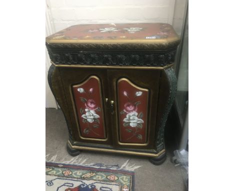 A hand painted cabinet the top with flowers and foliage above two doors the frieze moulding in the form of stylised acanthus 