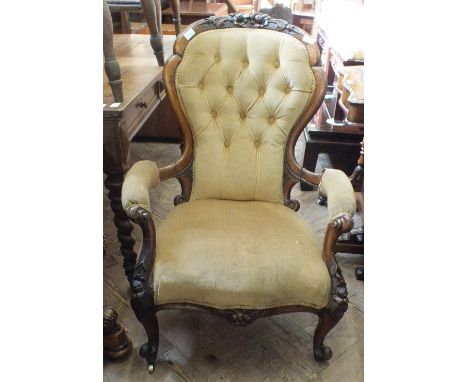 A Victorian mahogany saloon armchair with carved back and gold draylon button back upholstery