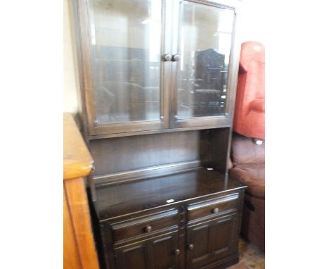A dark Ercol oak sideboard with glazed cupboards above