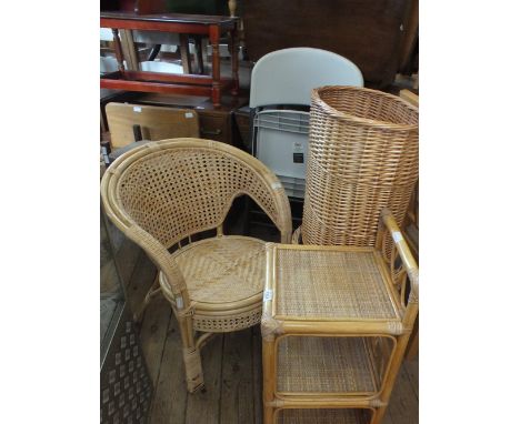 A selection of cane furniture including a tub chair, linen baskets and three tier shelf unit and a plastic folding chair