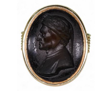 A GLASS INTAGLIO RING depicting Dante, in a closed back Georgian style setting, stamped 18ct. Finger size O1/2, weight 16.6gm