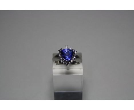 AN 18CT GOLD TANZANITE AND DIAMOND RING, with trillian cut tanzanite to a surround of brilliant cut diamonds to the plain tap