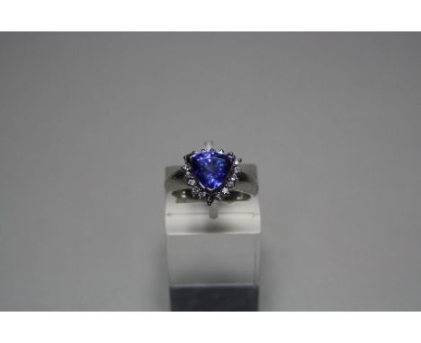 AN 18CT GOLD TANZANITE AND DIAMOND RING, with trillian cut tanzanite to a surround of brilliant cut diamonds to the plain tap