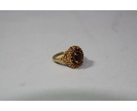 AN 18CT GOLD GARNET CLUSTER RING, with central oval garnet within a surround of further garnets and scalloped edge, ring size