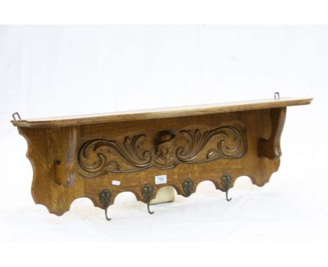 Golden Oak Hall Shelf with Coat Hooks, the back panel carved with a face mask and scrolls, 97cms long