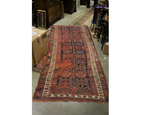 Middle Eastern Red Ground Wool Rug with Geometric Pattern surrounded by a Panel, 292cms x 124cms