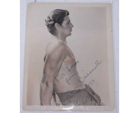 Johnny Weissmuller (1904-1984), a 3/4 length MGM Studio portrait of the actor and athlete as Tarzan, signed at an angle "For 