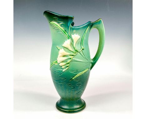 A single handled ceramic pitcher decorated with lavender and white clusters of flowers set against a green textured ground. R