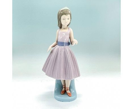 Glazed figurine of an elegant young lady in ballet costume waiting for her dance partner. Includes Lladro backstamp. This ite