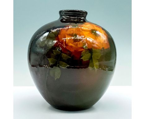 A glazed ceramic vase that is painted in color gradient of brown, green, and amber with yellow roses painted to the center. D