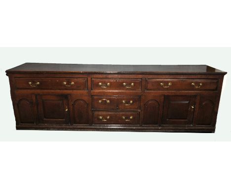 A Country House oak dresser base, mid 18th Century, the two plank top above a central flank of three drawers,  two frieze dra