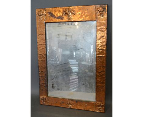 An Arts and Crafts Rectangular Copper Mirror, decorated with six embossed fleur de lis, 57 x 40 cms