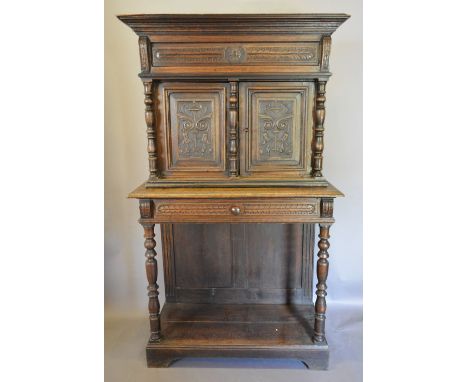 An Oak Cabinet on Stand, the moulded cornice above two carved doors flanked by turned pilasters, the lower section with a fri