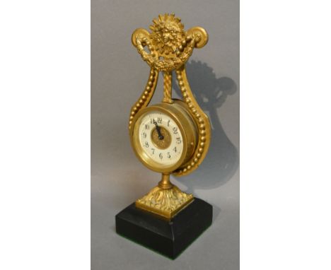 A French Gilded Mantle Clock in the form of a Lyre with central Sunburst, the enamel dial with Roman numerals all upon a squa