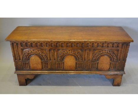 A 20th Century Green Oak Narrow Coffer, the moulded plank top above three carved panels flanked by stiles raised upon bracket