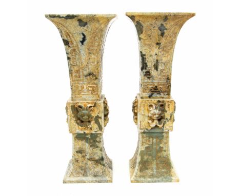 A pair of Chinese patinated green jade trumpet beaker vases (feng gu), each cuboid body carved on all four sides with a fire 